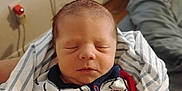Giovanni is registered to the contest to win money with this photo: baby, blanket, clothing, cozy, cute, face, indoor, infant, navy, newborn, onesie, peaceful, person, portrait, red, resting, sleeping, soft_light, striped, young_child
