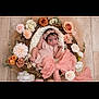 baby, child, cute, decor, floral_arrangement, flower_crown, headband, indoor, infant, knitted_outfit, nest, newborn, pastel_colors, pink_bow, portrait, posing, roses, smiling, soft_blanket, wooden_floor