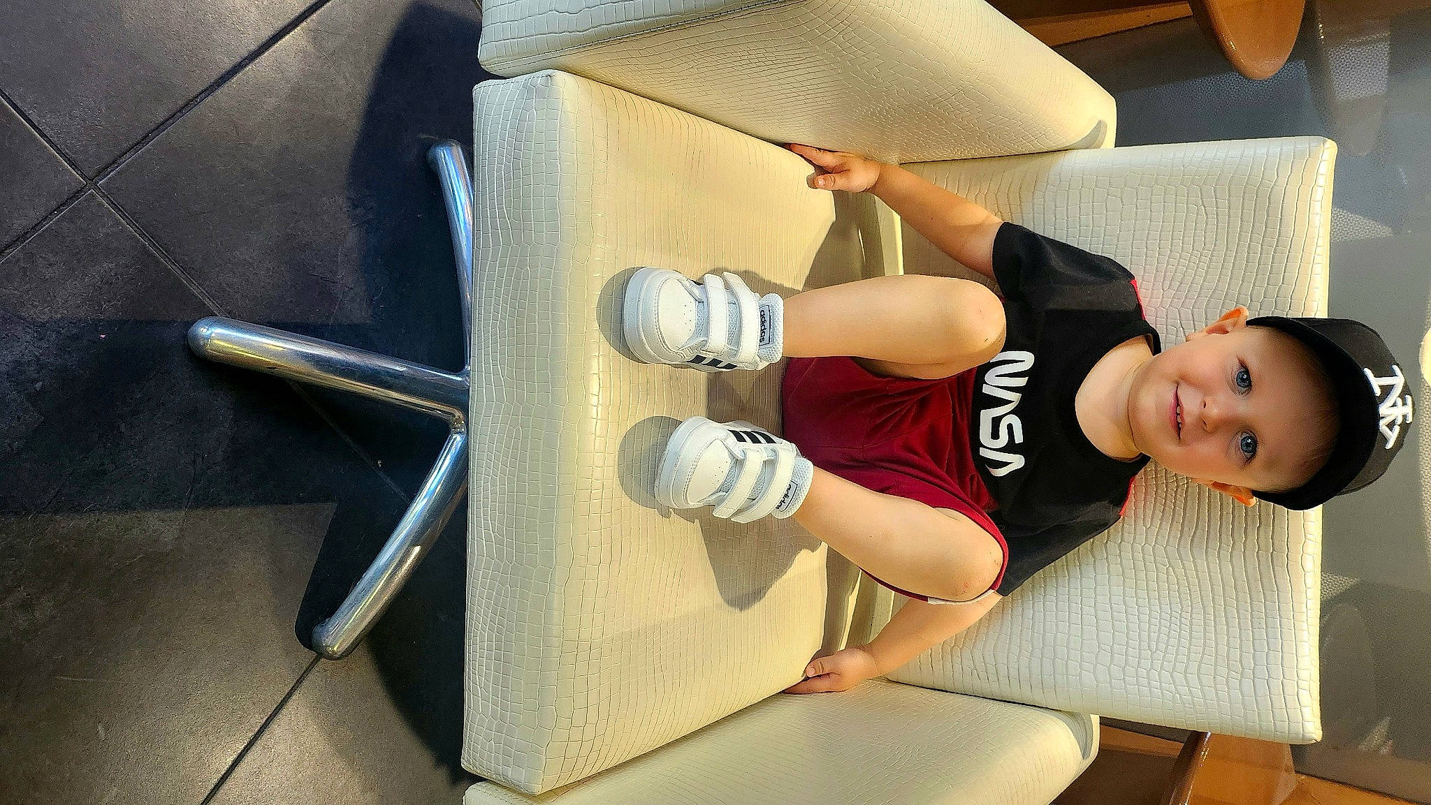 Mylan participe au concours pour gagner de l'argent avec cette photo : ceiling, chair, comfort, couch, elbow, flooring, fun, hat, headwear, human_leg, joy, knee, leg, person, shorts, smile, sportswear, stairs, t_shirt, table