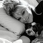 Winky participe au concours pour gagner de l'argent avec cette photo : woman, dog, bed, pillow, smile, black_and_white, portrait, indoor, cozy, laying, pet, affection, happy, hair, face, couch, turtleneck, cute, relaxing, friendly