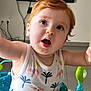 Axel a rejoint le concours — aidez-le/la à gagner de superbes lots ! activity_center, baby, child, curious, expression, floor, furniture, home, indoor, living_room, open_mouth, patterned_clothing, person, playtime, red_hair, seat, television, toddler, white_tank_top, wide_eyes