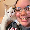 Max is registered to the contest to win money with this photo: adult, cat, cuddle, face, eyeglasses, smile, selfie, portrait, white_cat, indoor, closeup, pet, person, happy, teeth, gray_shirt, graphic_design, whiskers, ears, fur