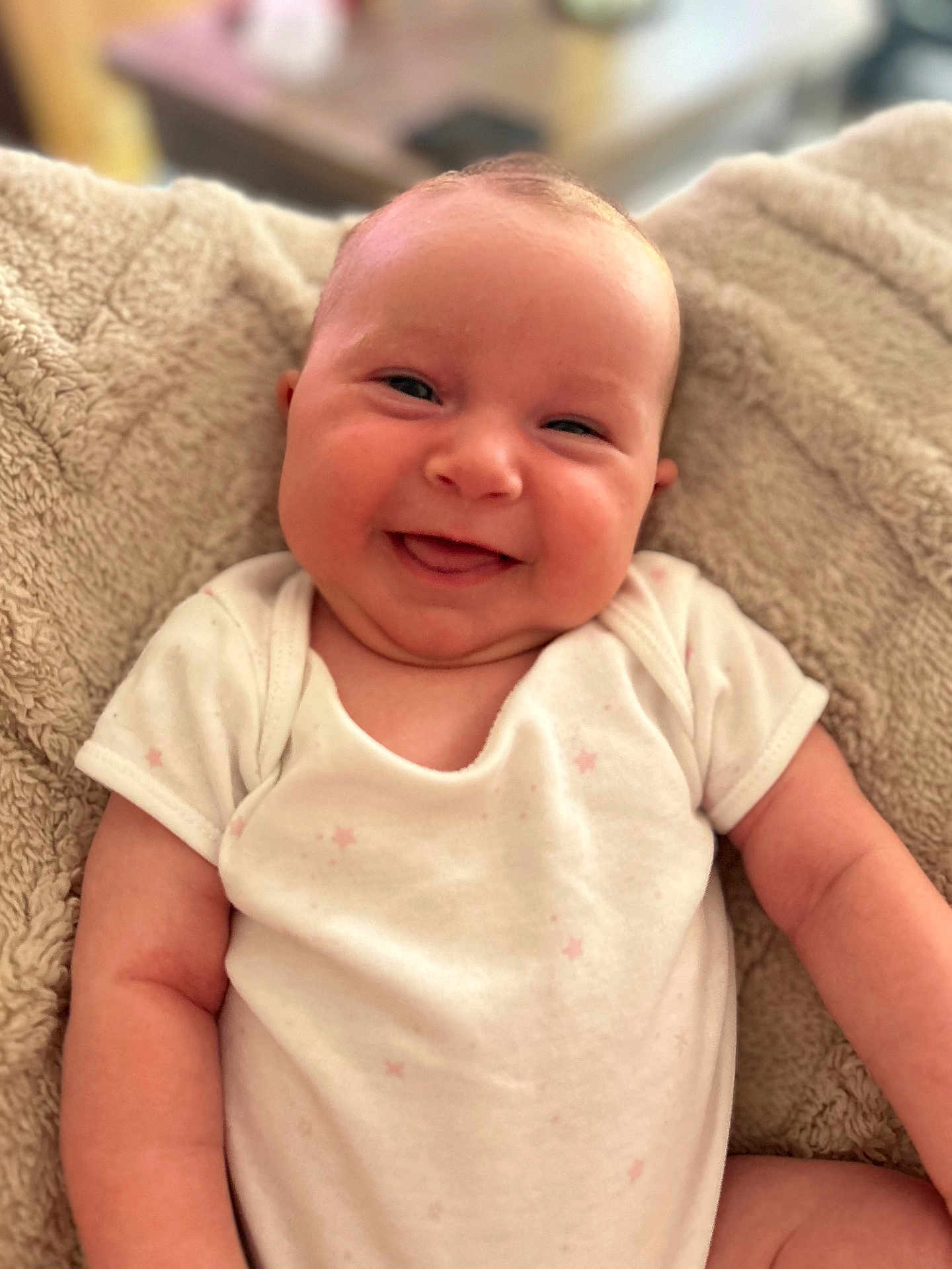Margot joined the competition — help win amazing prizes! baby, smiling, infant, onesie, blanket, cute, face, skin, chubby_cheeks, happy, portrait, child, soft_texture, cozy, indoors, person, newborn, relaxed, young_child, warm_lighting