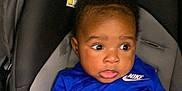 Liam joined the competition — help win amazing prizes! baby, infant, car_seat, blue_clothing, nike, child, cute, indoors, seat, young_child, person, apparel, sitting, attention, expression, hands, face, head, curious, transport