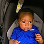 baby, infant, car_seat, blue_clothing, nike, child, cute, indoors, seat, young_child, person, apparel, sitting, attention, expression, hands, face, head, curious, transport