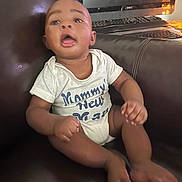 Liam joined the competition — help win amazing prizes! baby, child, infant, onesie, couch, leather, computer, monitor, keyboard, sitting, indoor, expression, mouth_open, hands, feet, face, young, casual, home, technology