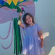 Brinley joined the competition — help win amazing prizes! child, girl, flower, bouquet, mural, wall, painting, dress, sandals, outdoor, sunlight, smile, happy, standing, concrete, colorful, young, nature, art, portrait