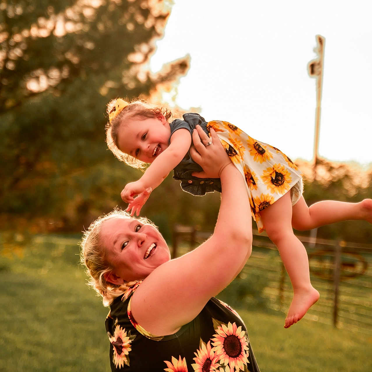Aspyn is registered to the contest to win money with this photo: barefoot, casual_clothing, child, daylight, family, fun, grass, greenery, happy, holding, joy, nature, outdoor, parent, playing, smiling, sunflower_dress, sunlight, sunset, woman