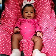 Dezeriah Sparks is registered to the contest to win money with this photo: baby, infant, child, pink_clothing, headband, bow, polka_dot, cushion, seat, socks, cute, smiling, indoors, portrait, young_child, resting, comfort, fabric, person, cozy