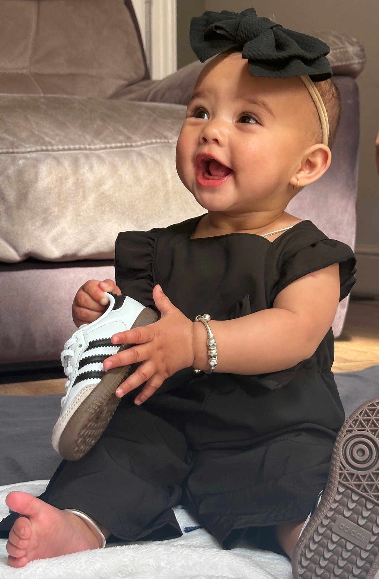 Maisha joined the competition — help win amazing prizes! baby, child, sneaker, black_clothing, headband, bracelet, smiling, sitting, indoor, couch, footwear, happy, accessory, person, portrait, cute, infant, fashion, soft_light, floor