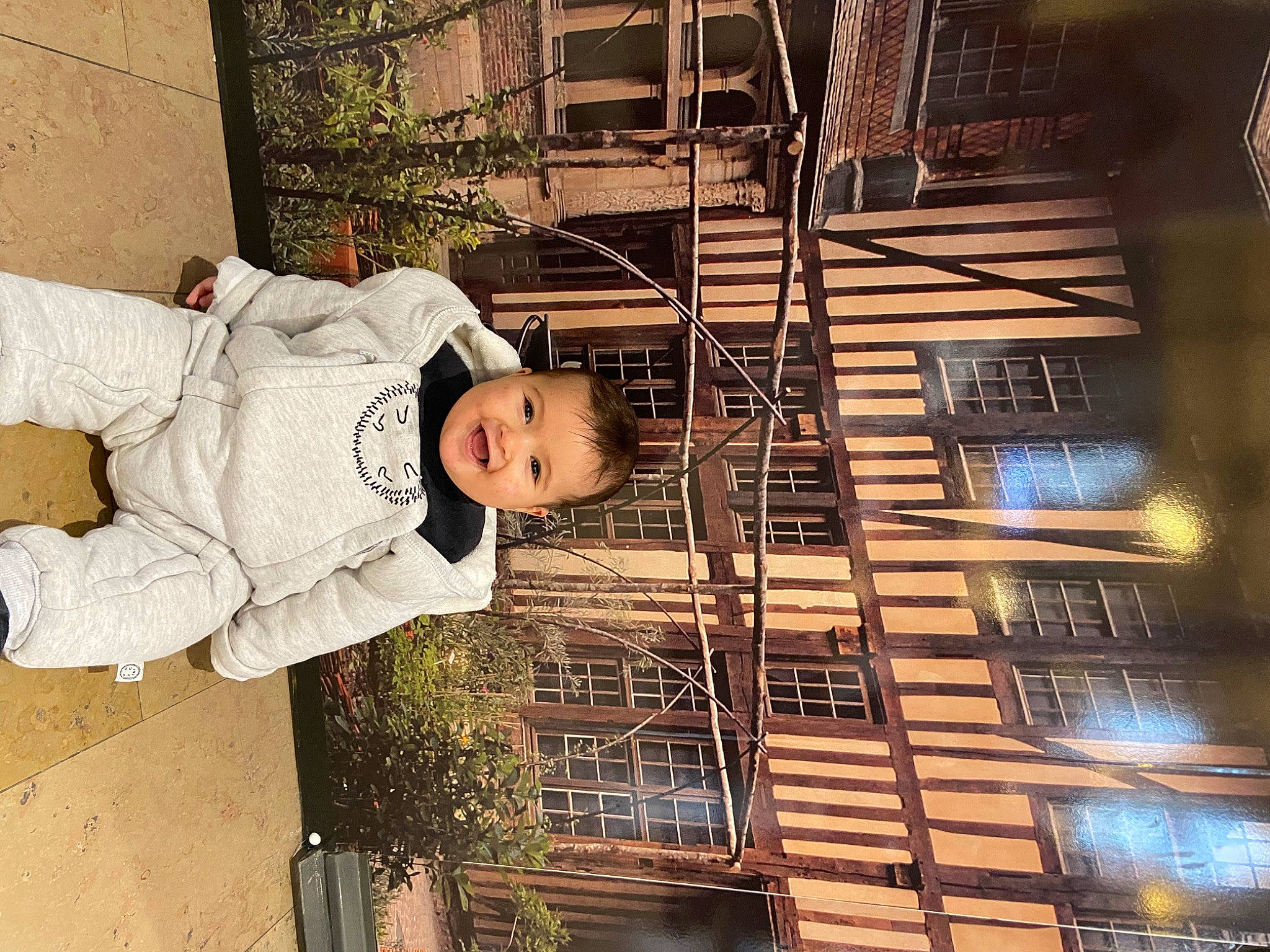 Jessim participe au concours pour gagner de l'argent avec cette photo : building, child, facade, fun, happy, hat, metal, pedestrian, person, plant, sitting, street, toddler, tree, wood