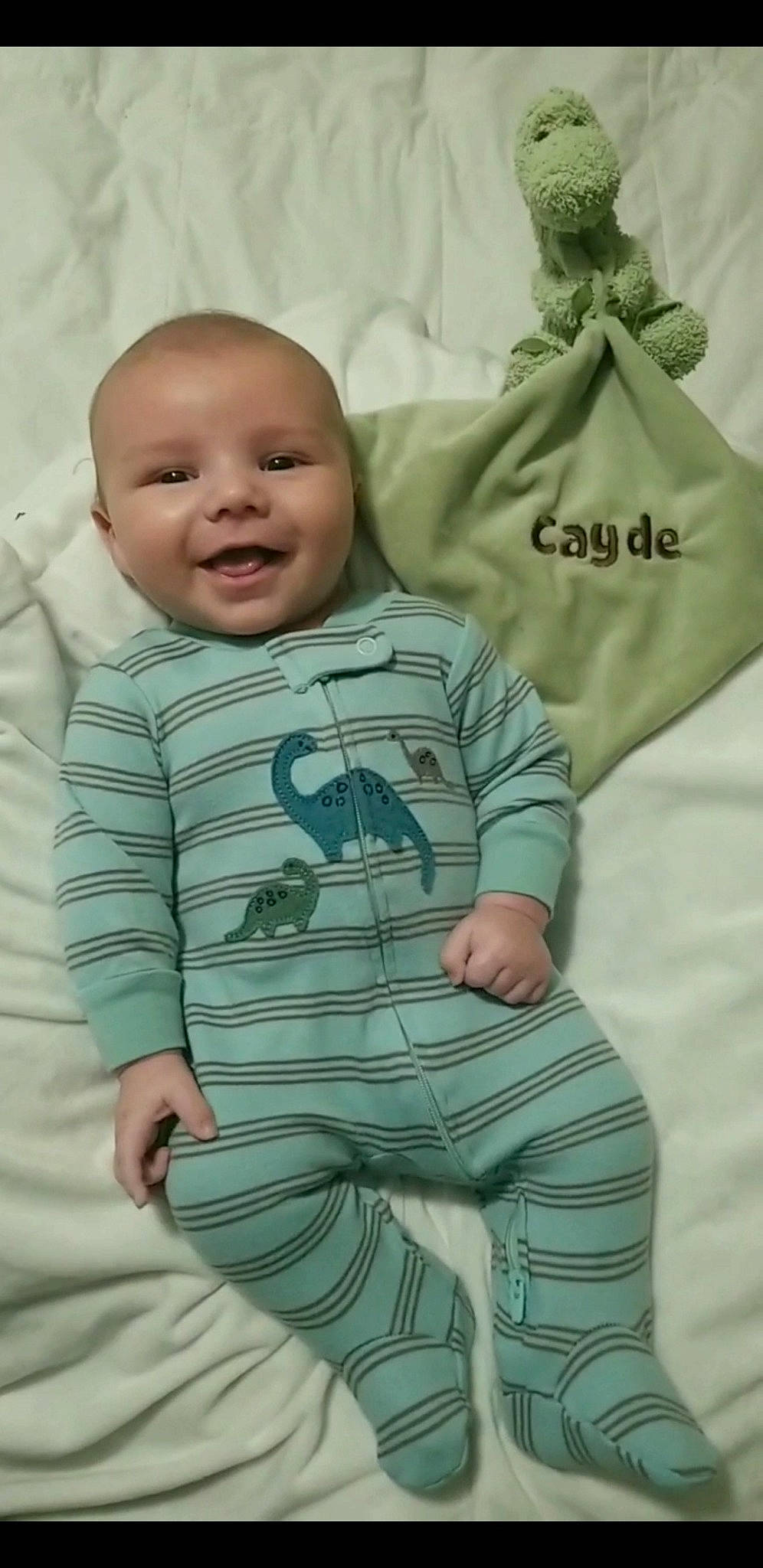 Cayde is registered to the contest to win money with this photo: baby, baby_products, baby_toddler_clothing, child, comfort, face, facial_expression, grey, happy, linens, mammal, outerwear, pattern, person, skin, sleeve, smile, t_shirt, textile, toddler
