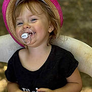 Kelly a rejoint le concours — aidez-le/la à gagner de superbes lots ! toddler, child, hat, pink_hat, pacifier, smiling, black_shirt, sitting, chair, outdoor, happy, blond_hair, portrait, baby, face, person, young_child, casual_clothing, nature_background, closeup