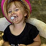 toddler, child, hat, pink_hat, pacifier, smiling, black_shirt, sitting, chair, outdoor, happy, blond_hair, portrait, baby, face, person, young_child, casual_clothing, nature_background, closeup