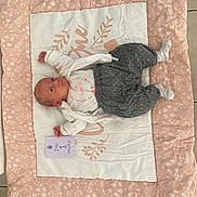Manon a rejoint le concours — aidez-le/la à gagner de superbes lots ! baby, infant, blanket, clothing, socks, floor, tile, card, milestone, person, cute, lying_down, pink, white, gray, pattern, soft, newborn, child, celebration