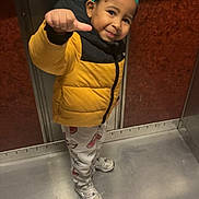 Yamin a rejoint le concours — aidez-le/la à gagner de superbes lots ! child, boy, yellow_jacket, paper_crown, elevator, thumbs_up, smile, patterned_pants, sneakers, indoor, metal_floor, metal_walls, happy, cute, standing, portrait, person, clothing, headwear, fun