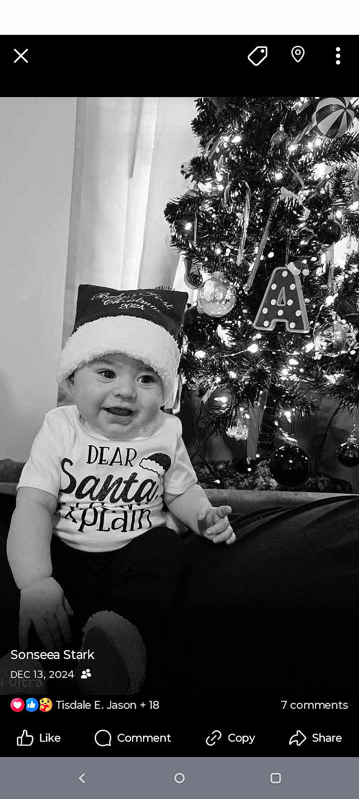 Ahari is registered to the contest to win money with this photo: baby, child, santa_hat, christmas_tree, ornaments, lights, holiday, festive, smiling, indoor, black_and_white, tshirt, cute, decoration, celebration, seasonal, happy, portrait, infant, christmas