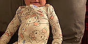 Rosita is registered to the contest to win money with this photo: baby, infant, smiling, onesie, hello_kitty, pillow, blanket, plaid, clothing, cute, child, lying_down, bed, indoor, face, person, happy, young, cozy, sleepwear