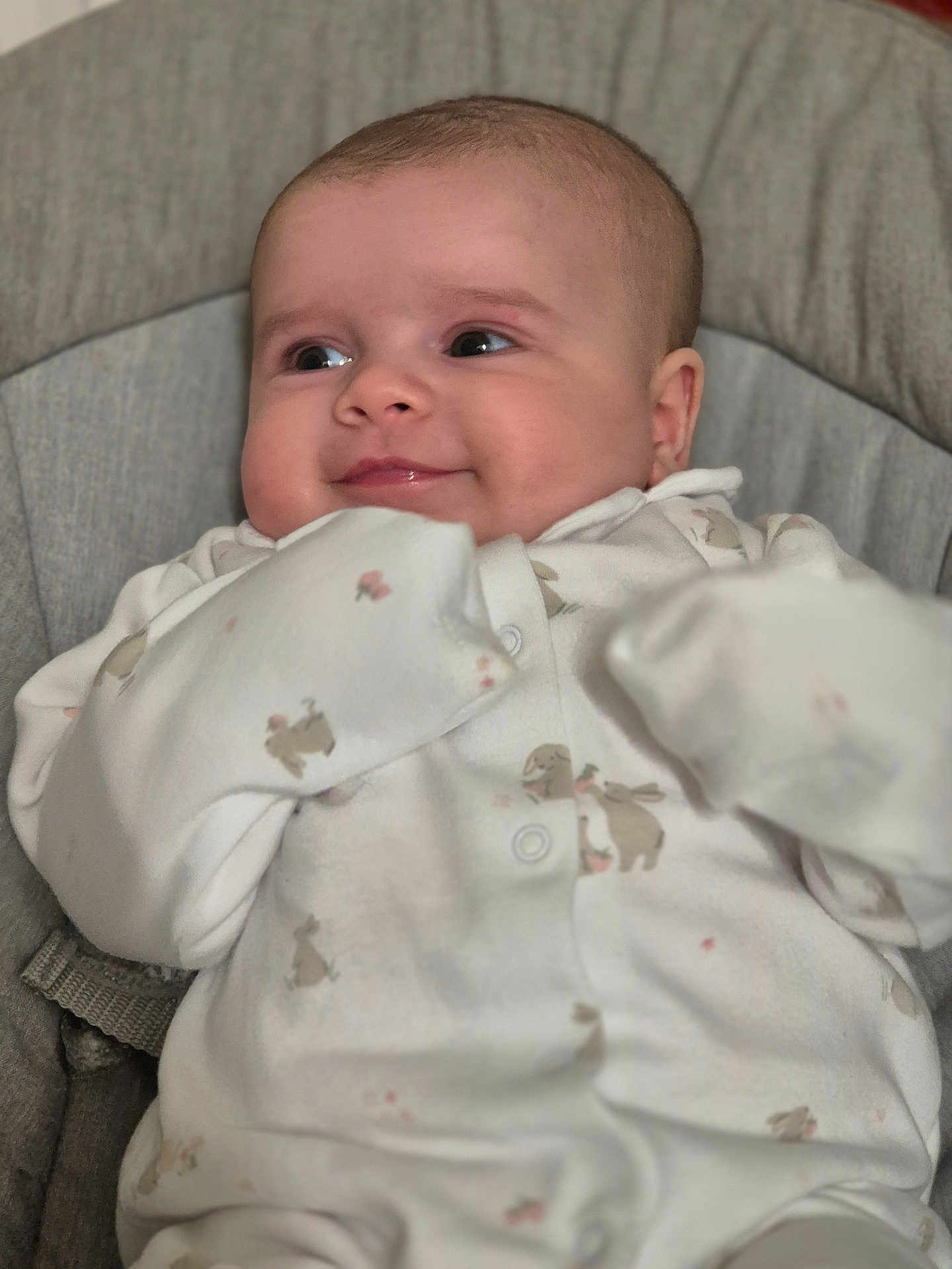 Daisy is registered to the contest to win money with this photo: baby, infant, smiling, onesie, bunny_print, cushion, seat, cute, soft_lighting, portrait, child, sleepwear, indoor, happy, young, face, skin, head, hand, cozy