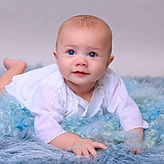 Declan joined the competition — help win amazing prizes! baby, infant, blue_eyes, white_clothing, soft_rug, fluffy_texture, portrait, cute, child, lying_down, hands, curious, gaze, studio_lighting, indoor, young_child, skin, head, face, expression