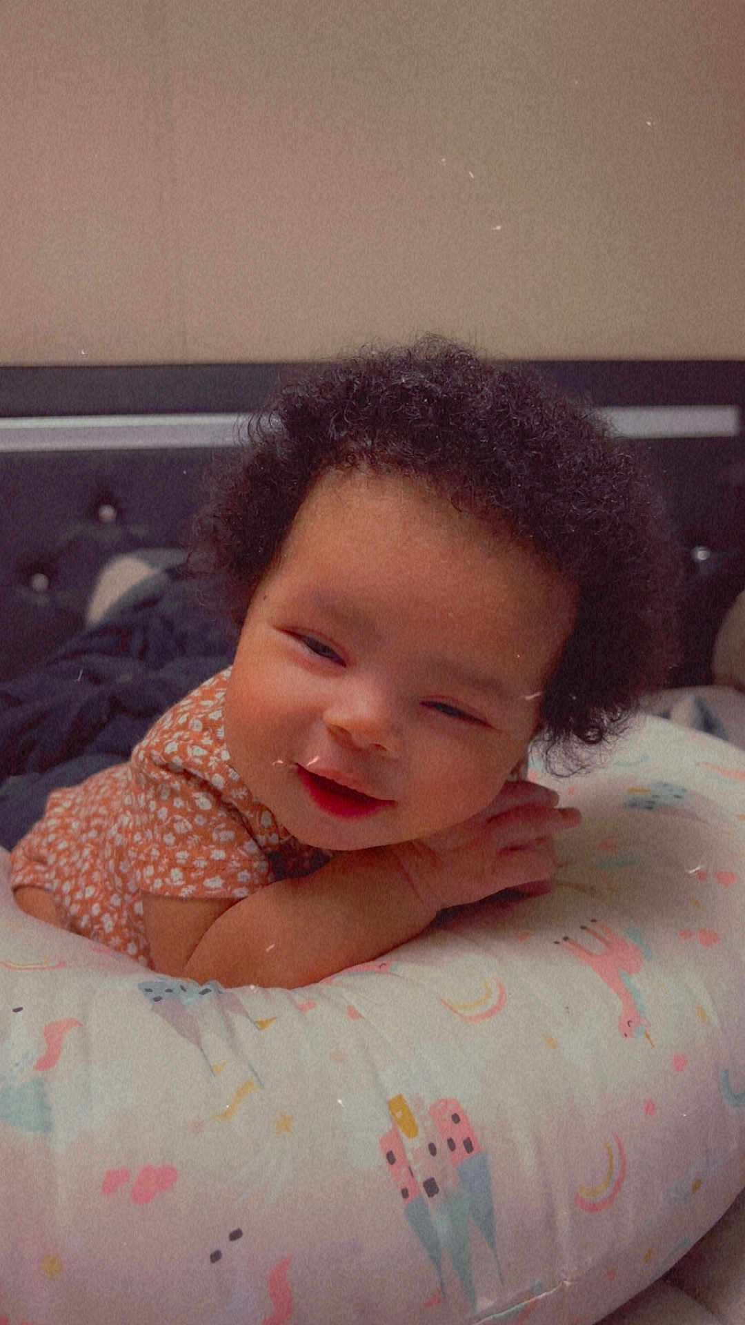 Anya joined the competition — help win amazing prizes! baby, curly_hair, smile, cushion, patterned, infant, clothing, bedroom, comfort, child, cute, portrait, laying_down, soft_light, happy, indoors, head, face, resting, toddler