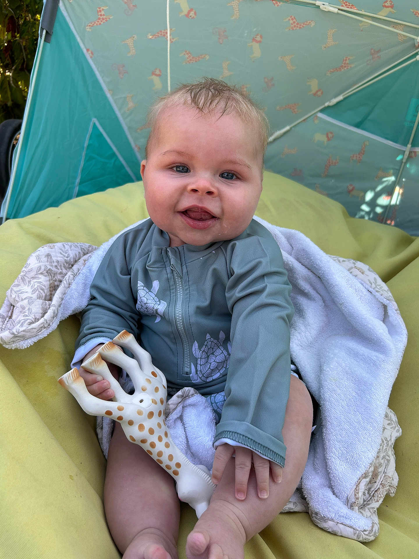 Noah participe au concours pour gagner de l'argent avec cette photo : baby, child, smiling, toy, giraffe, blanket, cushion, outdoor, tent, blue_clothing, happy, infant, cute, playful, person, portrait, relaxing, sunlight, nature, toddler