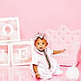 baby, child, girl, pink, birthday, blocks, one, headband, bow, dress, armchair, ottoman, balloon, floor, studio, portrait, cute, celebration, smiling, sitting