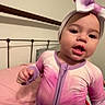 toddler, child, bedroom, bed, headband, onesie, purple, pink, metal_bedframe, person, indoor, expression, young_child, sleepwear, blanket, hand, face, infant, home, cute
