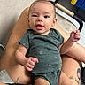 Sophia joined the competition — help win amazing prizes! baby, child, infant, onesie, green_clothing, smiling, winking, person, legs, tattoo, hand, indoor, chair, floor, wall, cute, happy, skin, seated, closeup