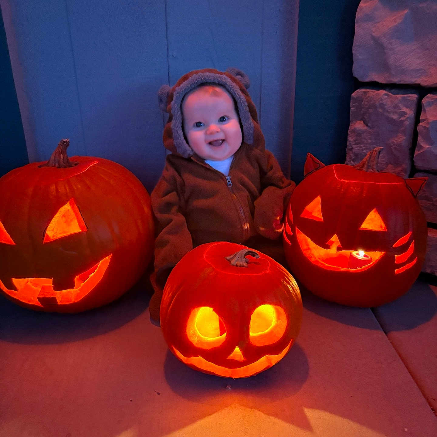Maya is registered to the contest to win money with this photo: baby, blanket, clothing, costume, face, festival, food, halloween, head, jack_o_lantern, person, plant, produce, squash, vegetable