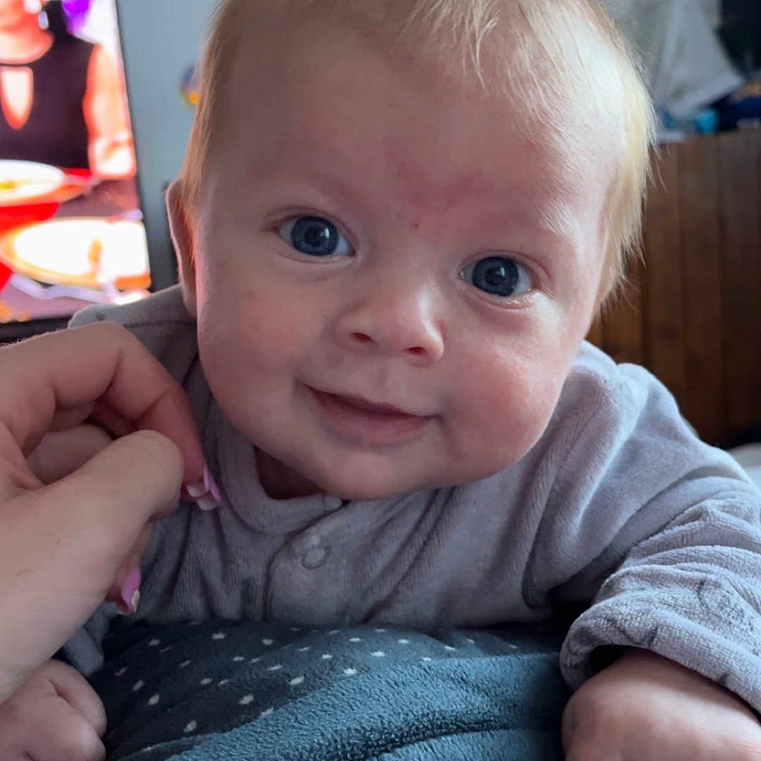 Jules participe au concours pour gagner de l'argent avec cette photo : baby, blanket, child, closeup, clothing, couch, cute, eyes, face, gentle, hand, home, indoor, infant, person, portrait, resting, smile, soft, young