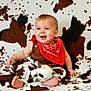 baby, child, smiling, red_bandana, plush_toy, cow_pattern, blanket, sitting, happy, indoor, cute, infant, clothing, foot, face, person, toy, brown, white, portrait