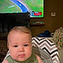William joined the competition — help win amazing prizes! baby, cheeks, child, curious, cute, electronics, face, furniture, green_shirt, high_chair, indoor, living_room, person, race_track, screen, seated, table, television, young, zigzag_pattern