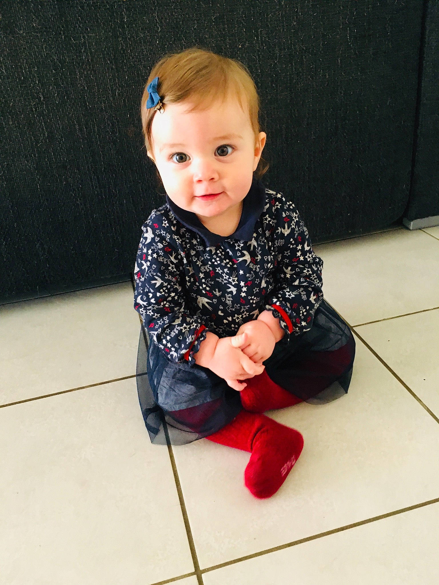Lucy a rejoint le concours — aidez-le/la à gagner de superbes lots ! baby, baby_toddler_clothing, carmine, cheek, child, electric_blue, eye, floor, flooring, fun, hardwood, human_leg, knee, pattern, person, sitting, sleeve, sock, t_shirt, toddler