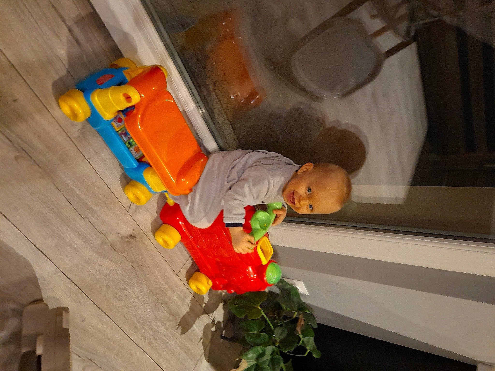 Maïwey a rejoint le concours — aidez-le/la à gagner de superbes lots ! baby_toddler_clothing, baby_toys, child, cleanliness, flooring, flowerpot, fun, hardwood, houseplant, orange, person, plant, plastic, room, toddler, toy, wood
