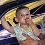 artificial_light, blue_pants, boy, car, car_door, casual_clothing, child, closeup, curious, hand, holding, night, outdoor, person, playful, portrait, ring, spiderweb_pattern, striped_shirt, watch