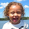 child, close_up, clouds, curly_hair, face, happy, lake, landscape, laughing, nature, outdoor, portrait, sky, smiling, summer, sunny, teeth, toddler, water, white_shirt