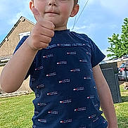 Kaéron participe au concours pour gagner de l'argent avec cette photo : child, boy, thumbs_up, outdoor, sunny, grass, sky, house, tree, shorts, tshirt, casual, summer, portrait, expression, confidence, yard, daylight, person, fashion