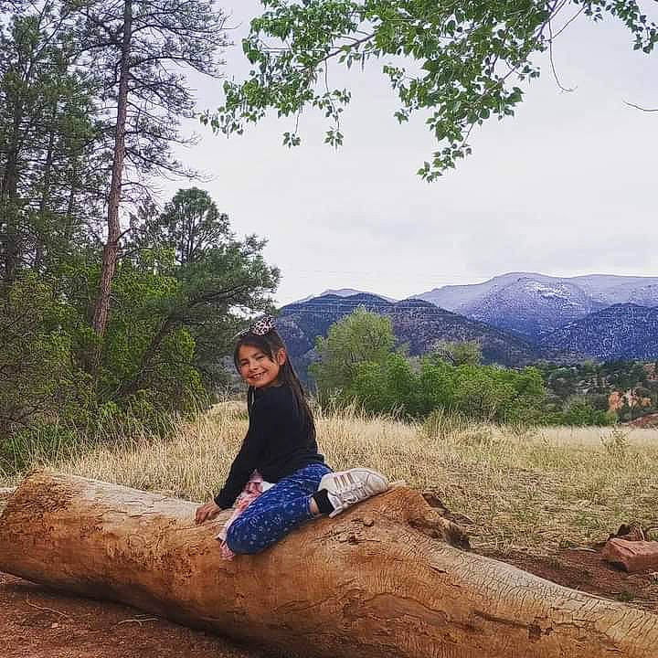 Leah is registered to the contest to win money with this photo: bedrock, branch, ecoregion, grass, happy, hat, highland, joy, landscape, mountain, mountainous_landforms, natural_environment, natural_landscape, people_in_nature, person, plant, plant_community, sky, tree, trunk