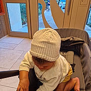 Marley a rejoint le concours — aidez-le/la à gagner de superbes lots ! baby, child, hat, knit_hat, sweater, indoor, stroller, curious, exploring, skin, hand, foot, window, door, floor, toddler, person, clothing, baby_clothing, candid