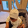 baby, child, hat, knit_hat, sweater, indoor, stroller, curious, exploring, skin, hand, foot, window, door, floor, toddler, person, clothing, baby_clothing, candid