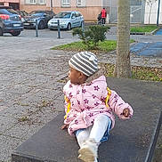 Boro Promise participe au concours pour gagner de l'argent avec cette photo : child, jacket, beanie, table, outdoor, urban, side_view, tree, cars, pavement, person, stroller, winter_clothing, curious, casual, parked_cars, street, daylight, leaf, metal