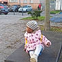 child, jacket, beanie, table, outdoor, urban, side_view, tree, cars, pavement, person, stroller, winter_clothing, curious, casual, parked_cars, street, daylight, leaf, metal
