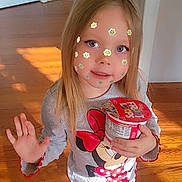 Taegan joined the competition — help win amazing prizes! child, girl, face_stickers, flower_stickers, cereal_cup, froot_loops, minnie_mouse_shirt, jeans, long_hair, blue_eyes, smile, hand_wave, standing, wood_floor, indoor, doorway, sunlight, portrait, cute, snack