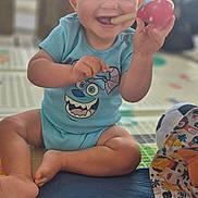 Amaël a rejoint le concours — aidez-le/la à gagner de superbes lots ! baby, blue_clothing, bright_eyes, cheerful, child, colorful, cute, face, foot, hand, happy, indoor, infant, onesie, patterned_blanket, playmat, playtime, sitting, smiling, toy