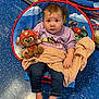 baby, blanket, chair, child, colorful, cute, floor, footwearless, happy, indoor, jeans, looking_up, paw_patrol, person, plush_toy, portrait, purple_sweatshirt, sitting, soft_toy, toy_store