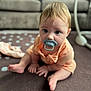 baby, pacifier, carpet, polka_dot, couch, indoor, child, sitting, curious, blond_hair, floor, home, infant, cute, close_up, person, soft_light, young_child, casual_clothing, background_blur