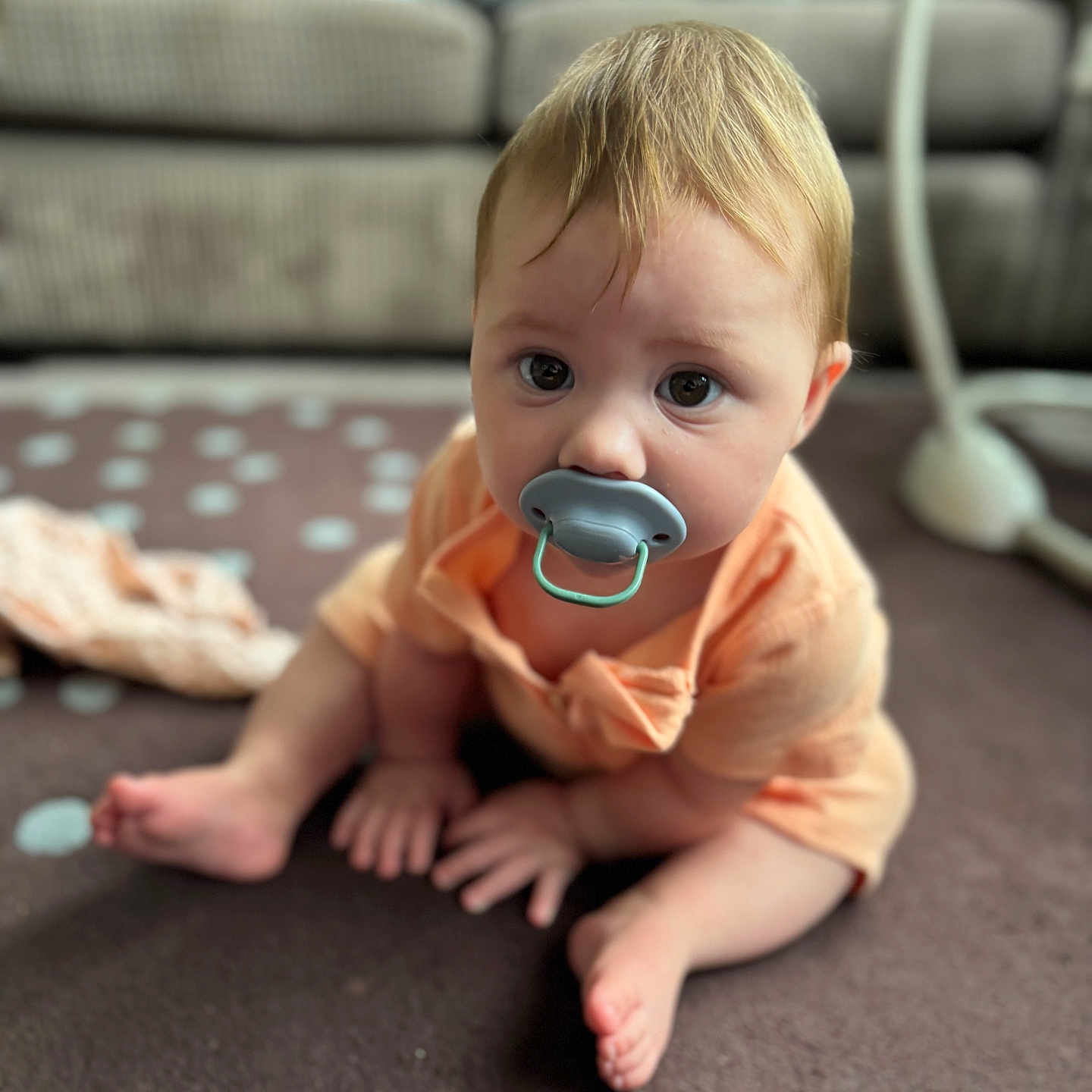 Mollie-Blake joined the competition — help win amazing prizes! baby, background_blur, blond_hair, carpet, casual_clothing, child, close_up, couch, curious, cute, floor, home, indoor, infant, pacifier, person, polka_dot, sitting, soft_light, young_child