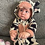 adorable, baby, child, clothing, costume, couch, cow_costume, cute, expression, eyes, face, furniture, hood, indoor, infant, onesie, plush_toy, sitting, sofa, soft_texture