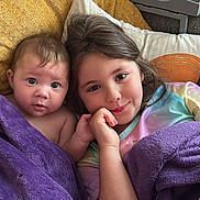 Mollie-Blake joined the competition — help win amazing prizes! baby, child, sibling, couch, blanket, purple_blanket, smile, face, happy, indoor, homedecor, pillow, tie_dye, person, candid, cute, toddler, relaxing, cozy, portrait